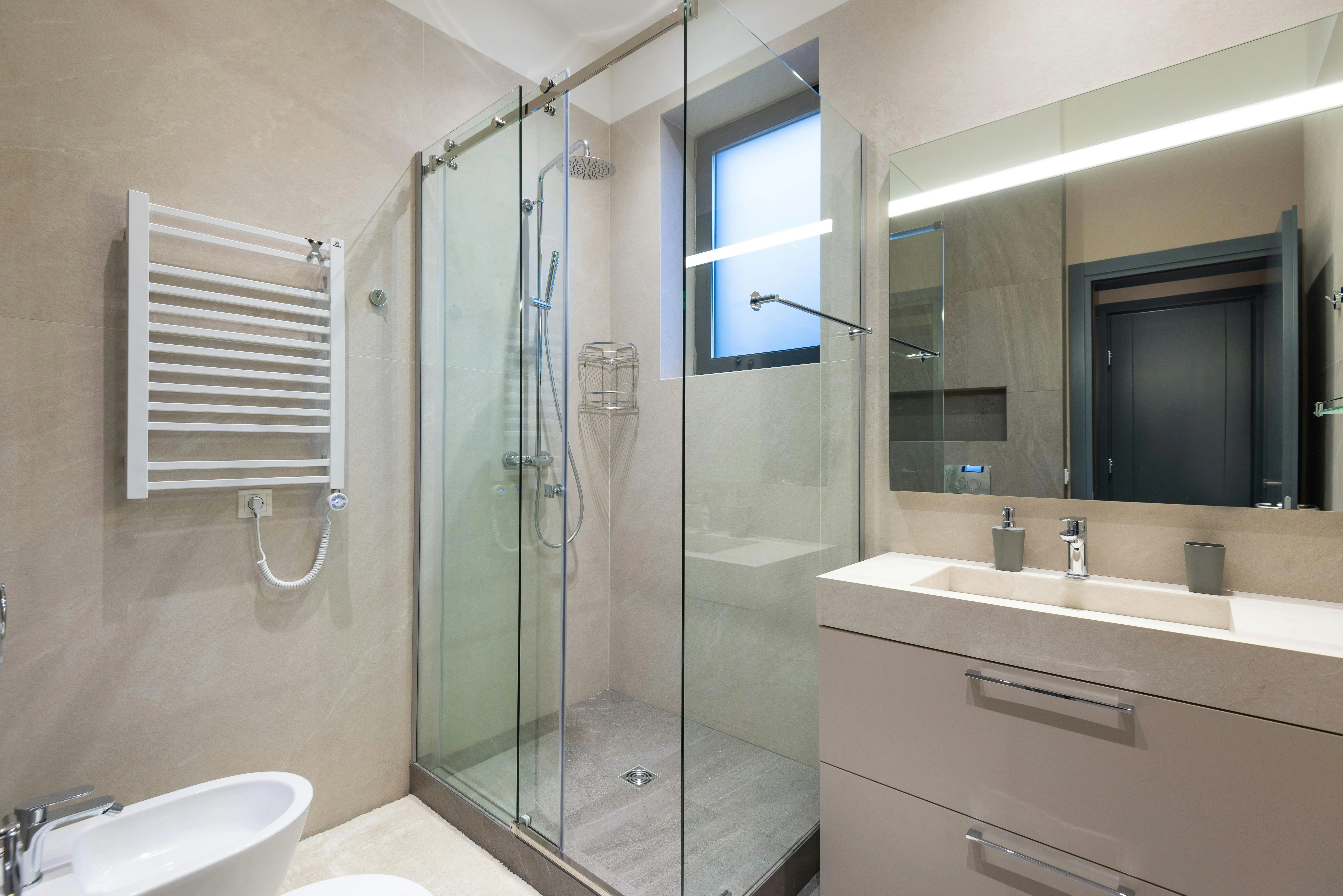 Salle de bain rénovée avec douche à paroi vitrée et meuble vasque — SDR Plomberie La Baule